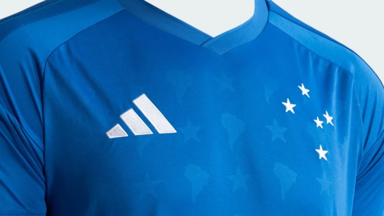 Camisa azul do Cruzeiro com logo Adidas, cinco estrelas brancas e marca d'água de mapas.