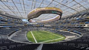 Interior do SoFi Stadium, Los Angeles, com campo, arquibancadas e telão 'SoFi Stadium', 'Hyundai', 'Samsung'.