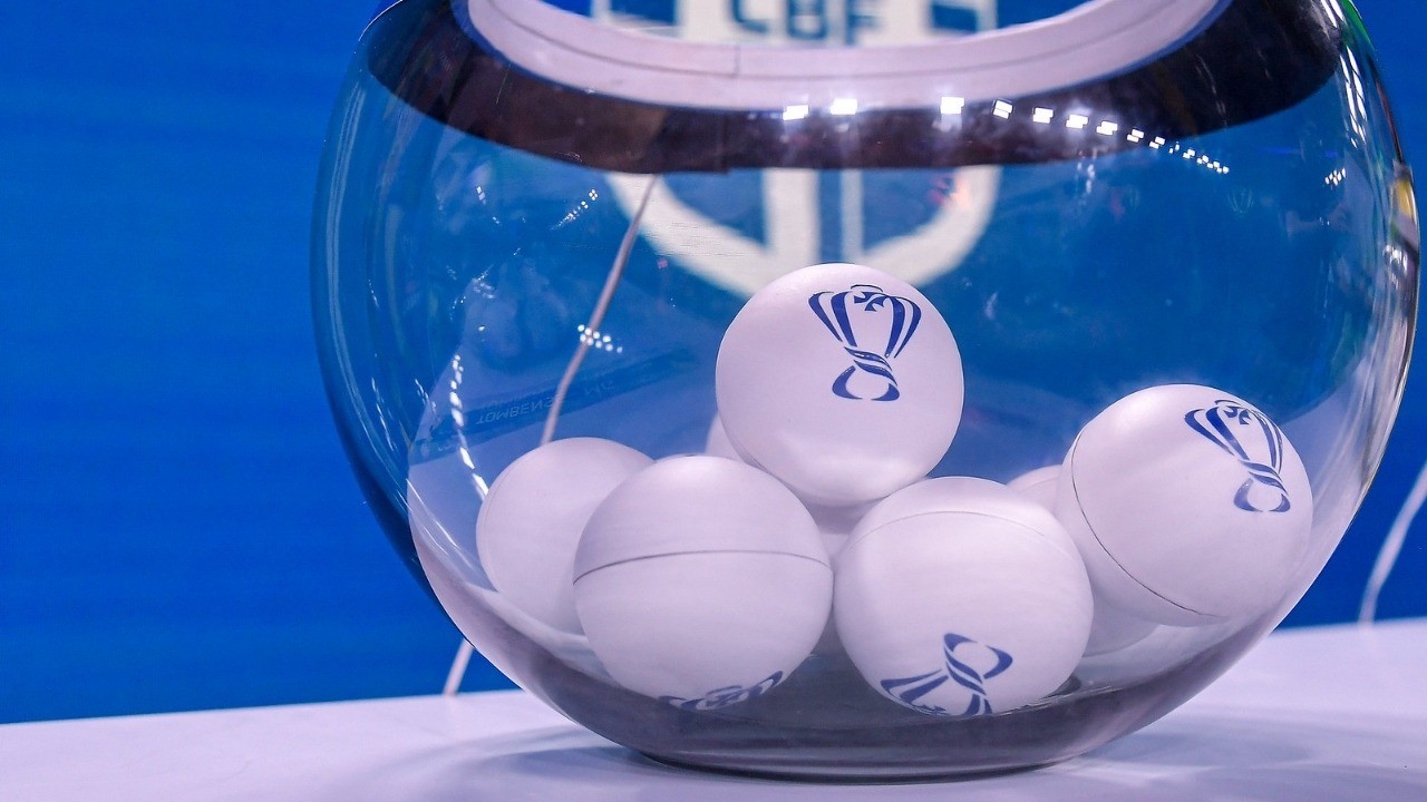 Globo de vidro transparente com bolas brancas exibindo logotipo de troféu azul, em fundo azul.